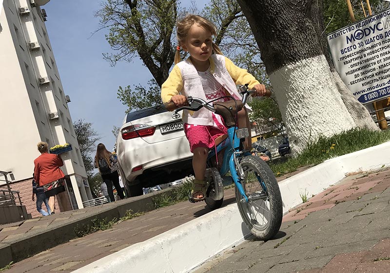 Ребенок съезжает на велосипеде с бордюра